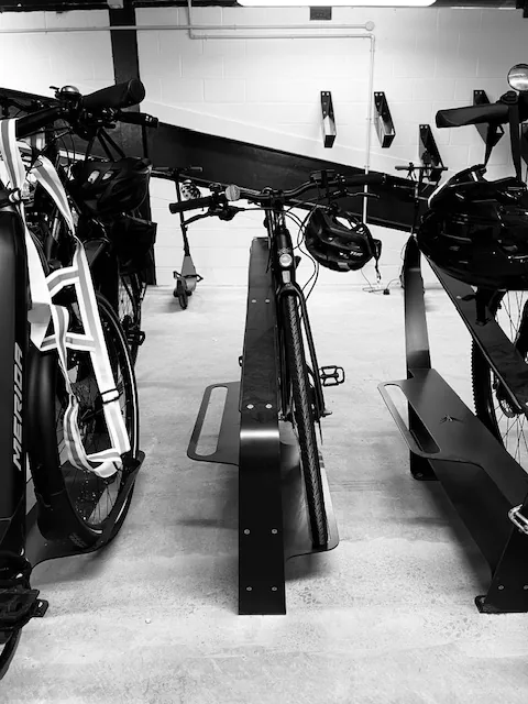Velohawk floor racks holding e-bikes in a basement bike room, with wall racks behind