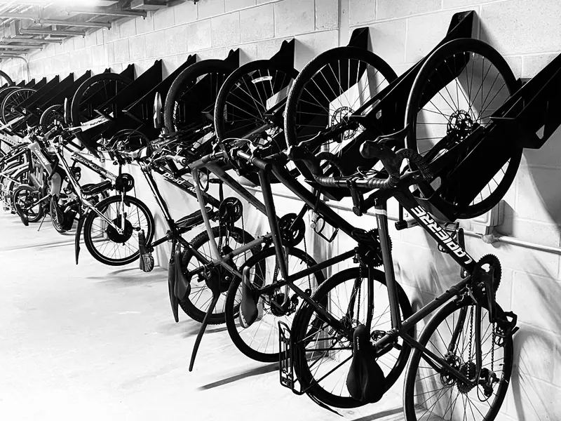 Row of Velohawk Kāhu wall racks holding bikes along a basement bike room wall